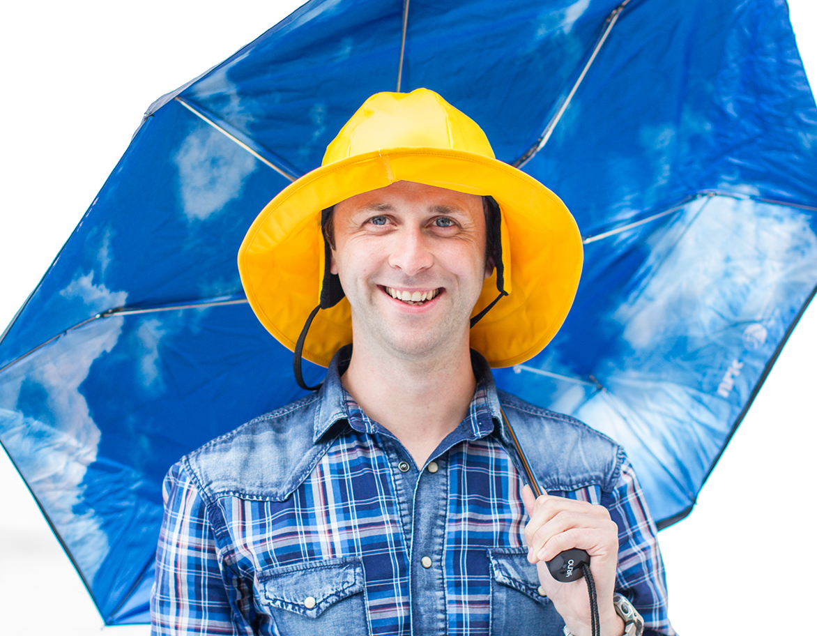 Anders Sivle med sydvest på hodet smiler mot kamera mens han holder en åpnet paraply.