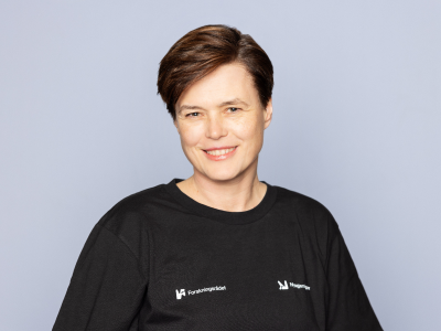 Dame som står foran en grå bakgrunn og smiler til kameraet