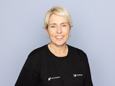 Dame som står foran en grå bakgrunn og smiler til kameraet