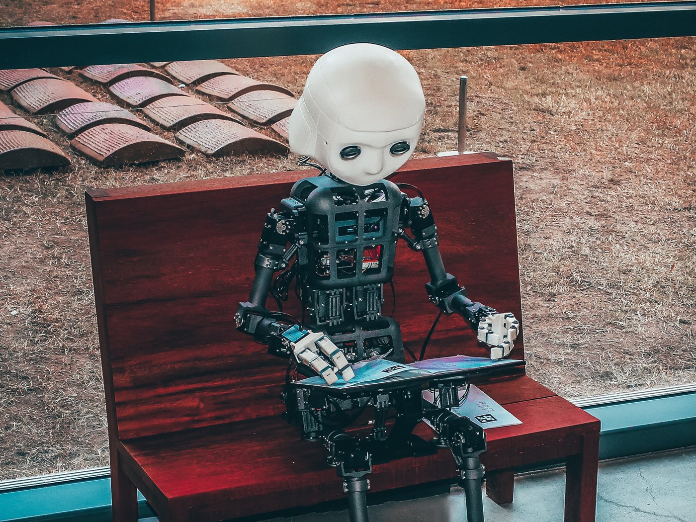 Robotmenneske som sitter på en benk og ser i en brosjyre