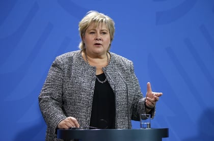 Statsminister Erna Solberg står bak en talerstol og snakker