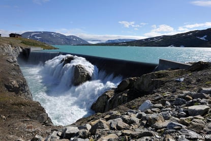 Oppdemmet vann på høyfjellet, vannet flommer over kanten av demningen