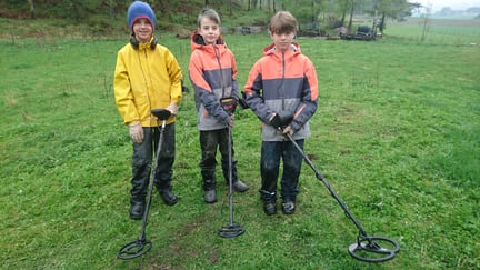 Tre gutter med metalldetektorer står ute i naturen