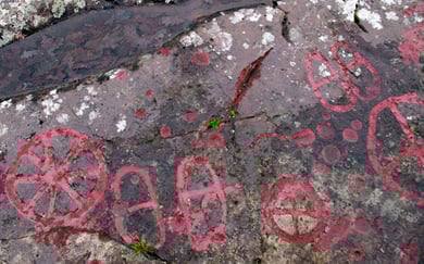 Røde helleristninger på en stein.