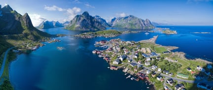 Oversiktsbilde av Reine i Lofoten om sommeren, med blått hav og blå himmel. Foto: Shutterstock