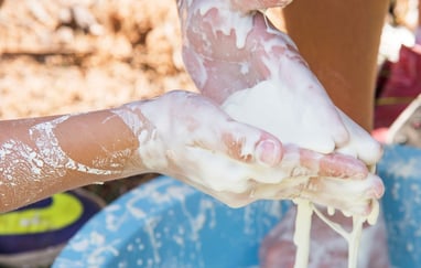 Nærbilde av hender som tar på en ikke-newtoniansk væske laget av vann og maisenna