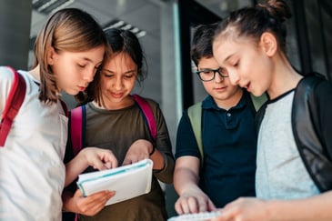 Fire elever står i gruppe og diskuterer