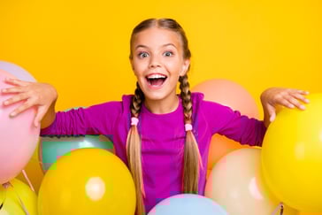 Jente sitter blandt masse fargerike ballonger