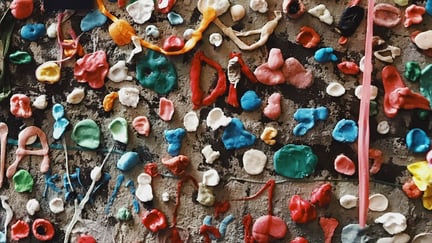 Tygde tyggegummier i mange farger festet på vegg