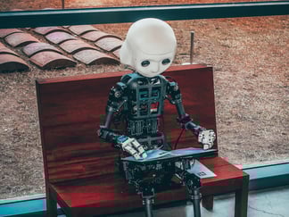 Robotmenneske som sitter på en benk og ser i en brosjyre