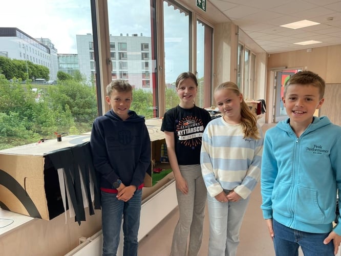 Femteklasseelevene Fredrik, Olivia, Hedda og Olav står og smiler foran følelsesboksene sine