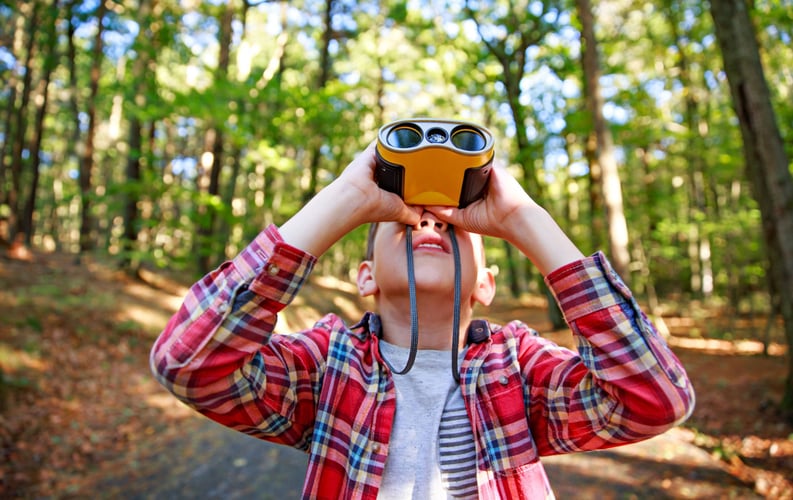 Gutt i skogen med gul kikkert