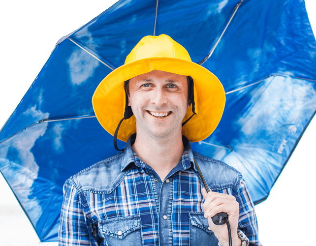 Anders Sivle med sydvest på hodet smiler mot kamera mens han holder en åpnet paraply. 