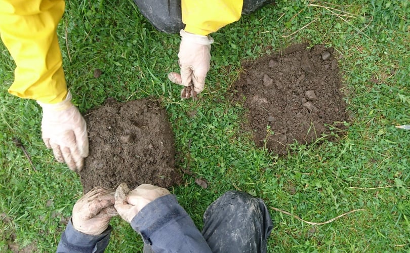 Hender leter etter metall i et lite jordstykke