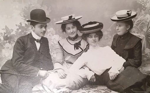 Gammelt fotografi av en gruppe mennesker i finstasen på 1900-tallet.