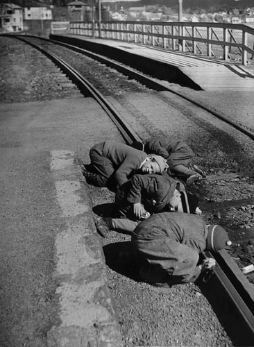 Gutter som er fotografert i 1950, liggende med øret inntil togskinnene for å høre når toget er på vei.