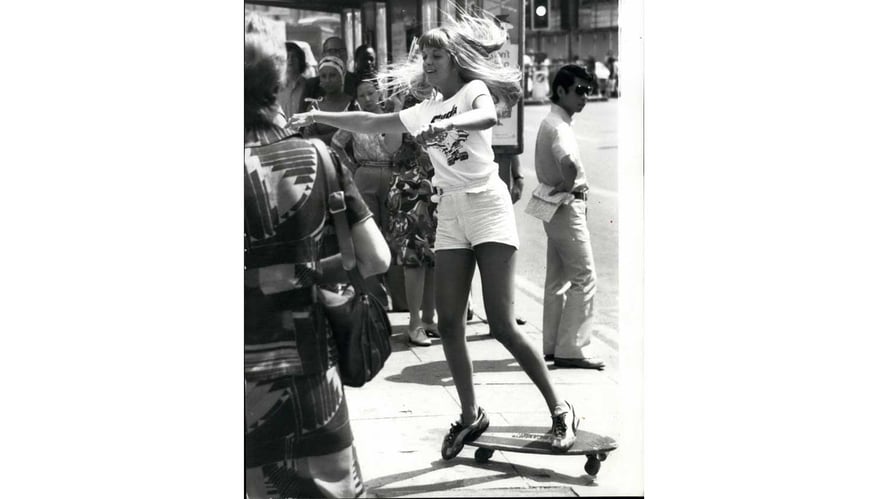 svarthvitt bilde av glad jente som skater på gata på 70-tallet