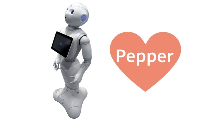 En hvit robot med skjerm på magen og et rødt hjerte med teksten Pepper