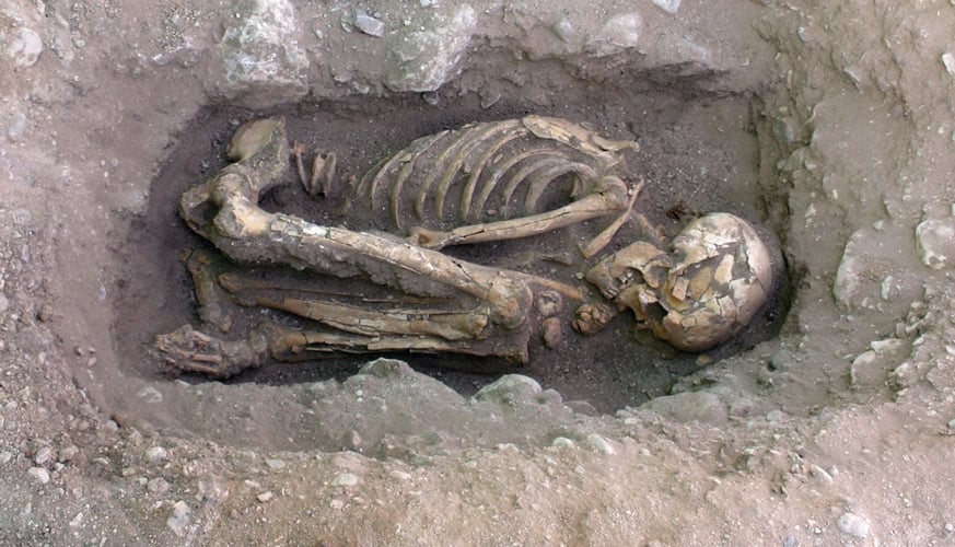 Mennskeskjelett i utgravd hull i bakken