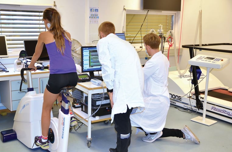 Dame sykler på trimsykkel mens forskere følger med