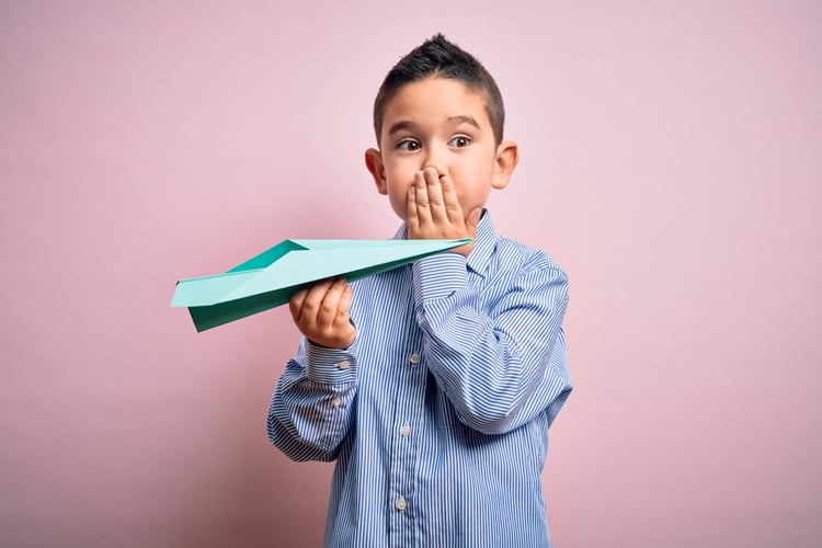 En gutt holder et papirfly i hånden