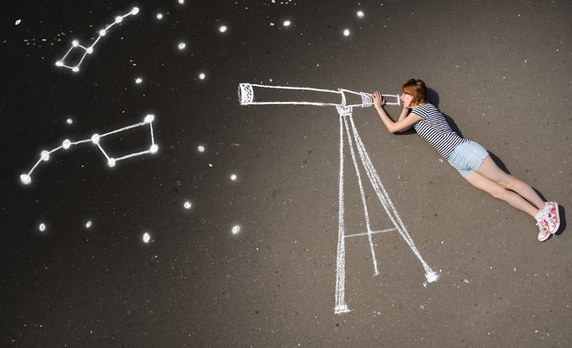 En som later som hun ser på stjernene med en stjernekikkert som er tegnet på bakken