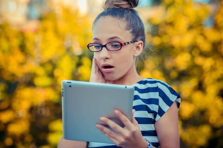 En jenter er tydelig sjokkert av hva hun leser på nettbrettet hun holder i hånden.