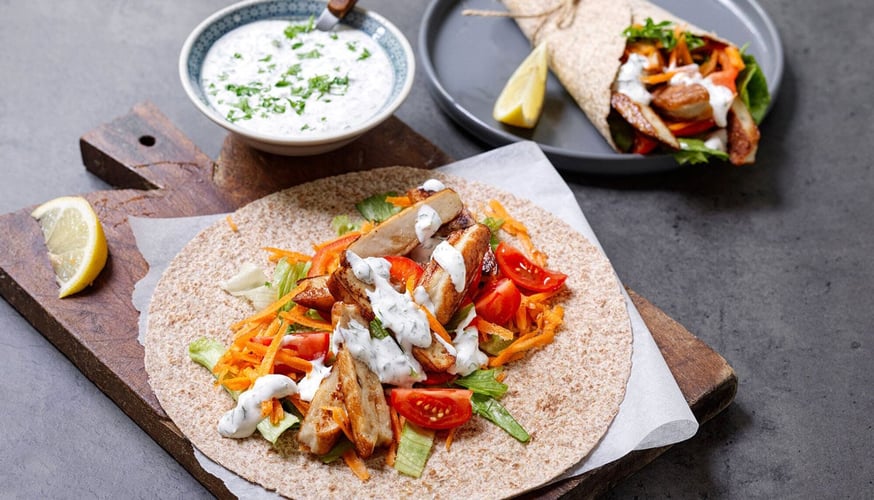 Foto av måltid med en grov wrap med salat, gulrot, tomat og fisk