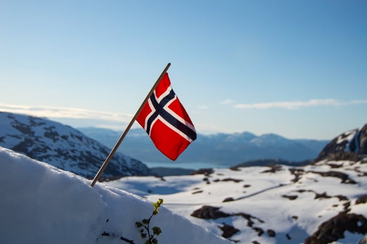 Et norsk flag plassert i snøen på fjellet
