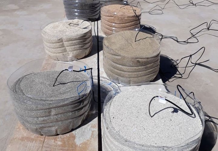 Plastbeholdere med sand i ulike farger og med temperaturmålere i