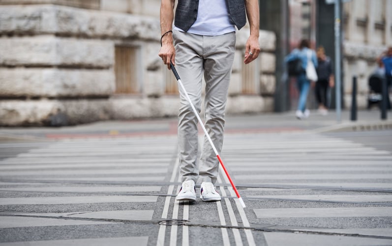 Mann med hvit stokk krysser gaten