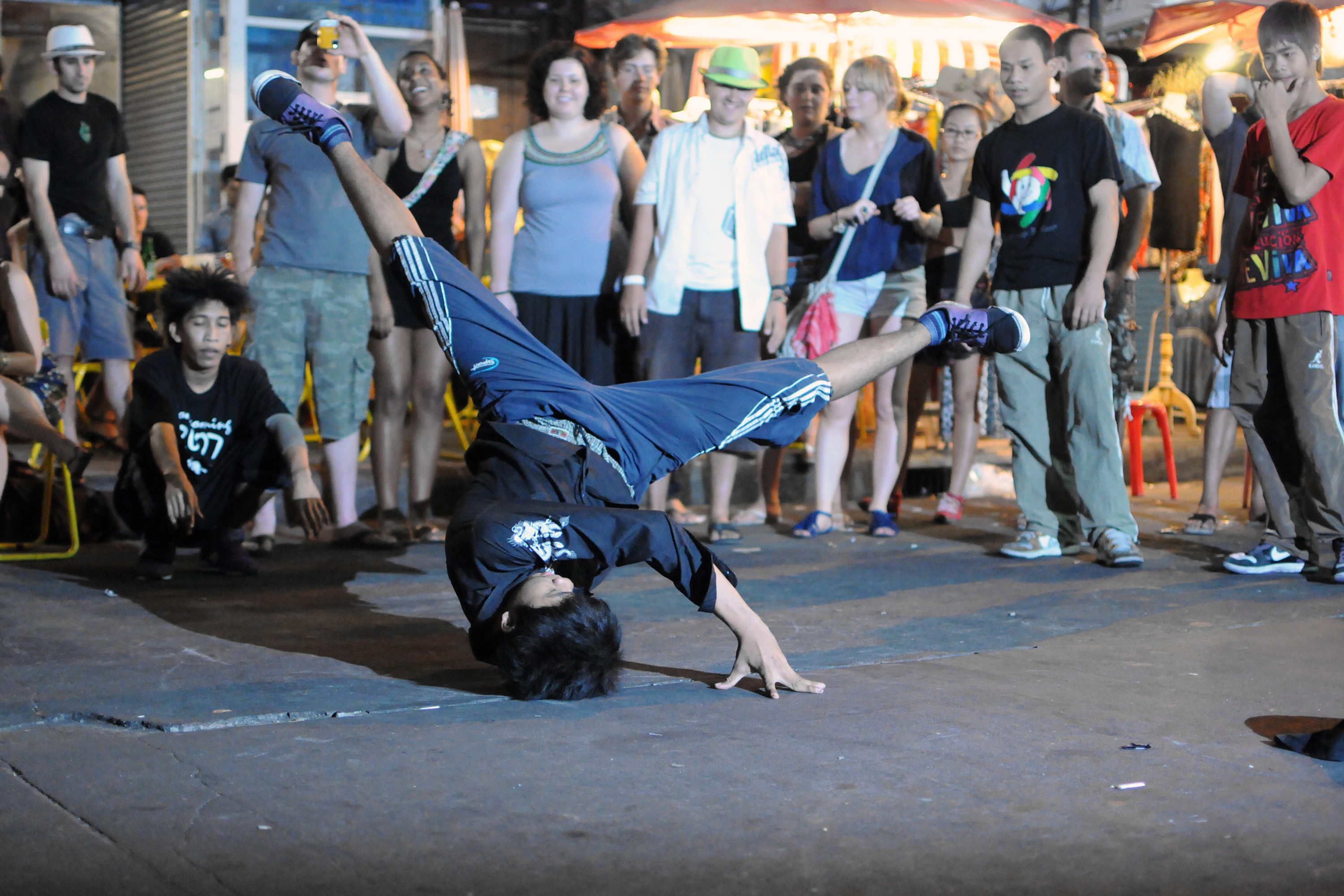 En som danser breakdance mend tilskuere som står rundt og ser på.