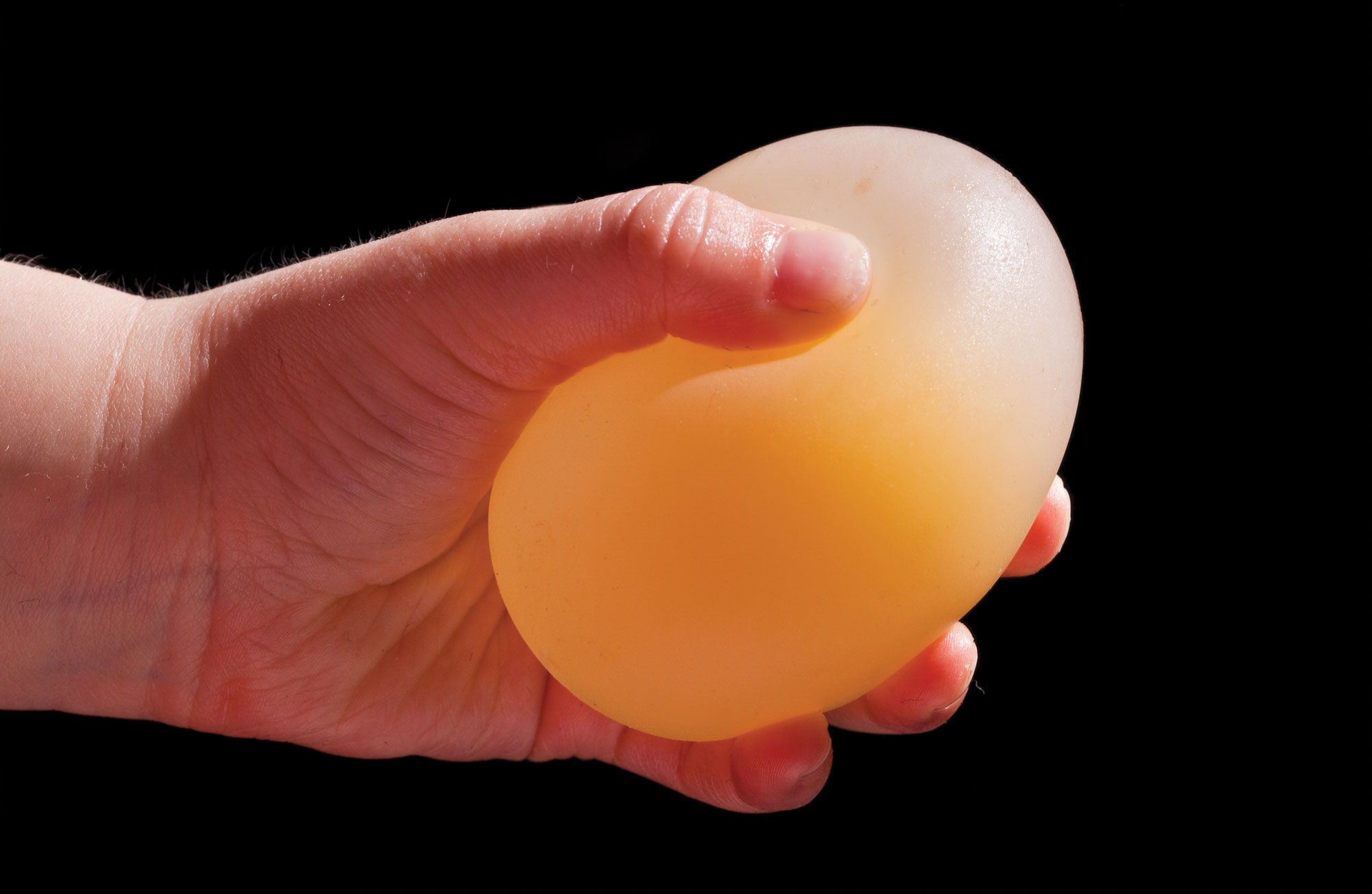 Hånd klemmer på gummiaktig egg som har ligget i eddik